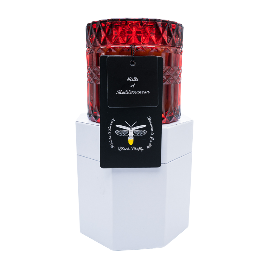 Red glass candle with a white base and black label on a white background