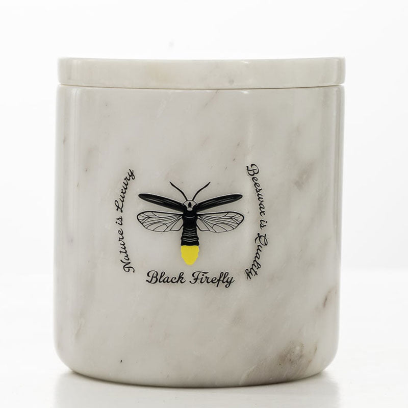 Snow of Lesotho - White Marble -textured candle jar with black firefly illustration and text on a white background