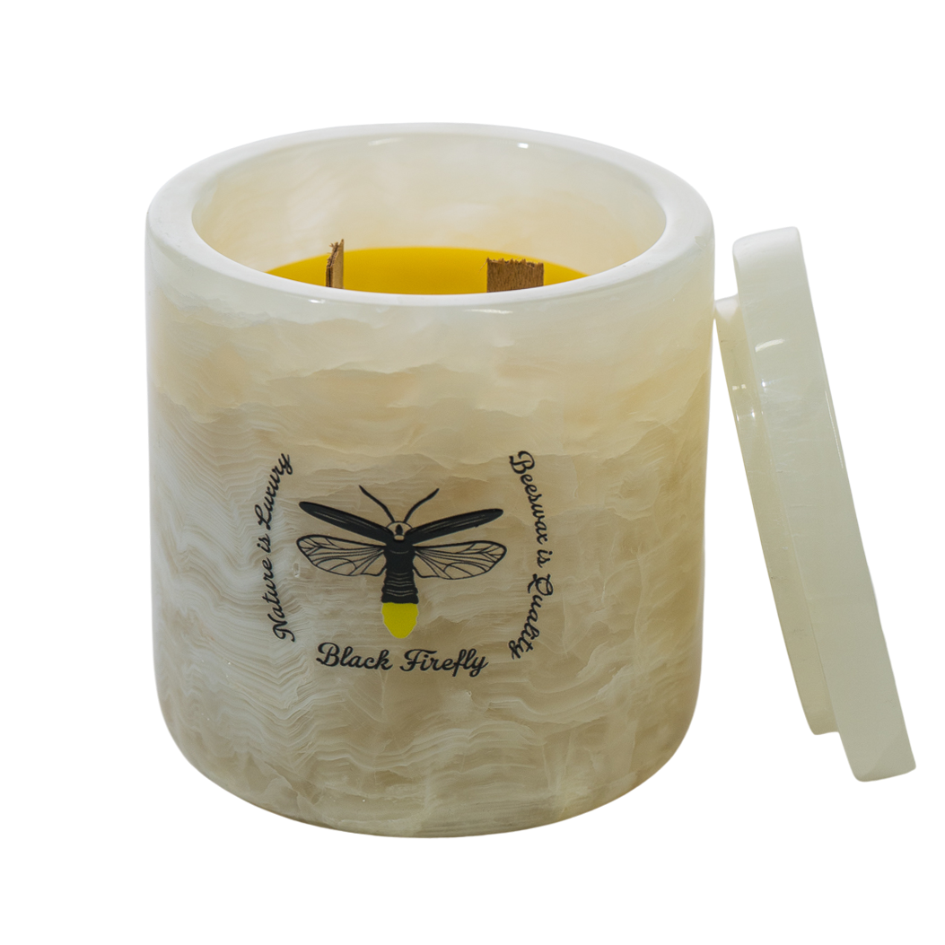 Cylindrical candle with a lid featuring a black firefly design on a white background