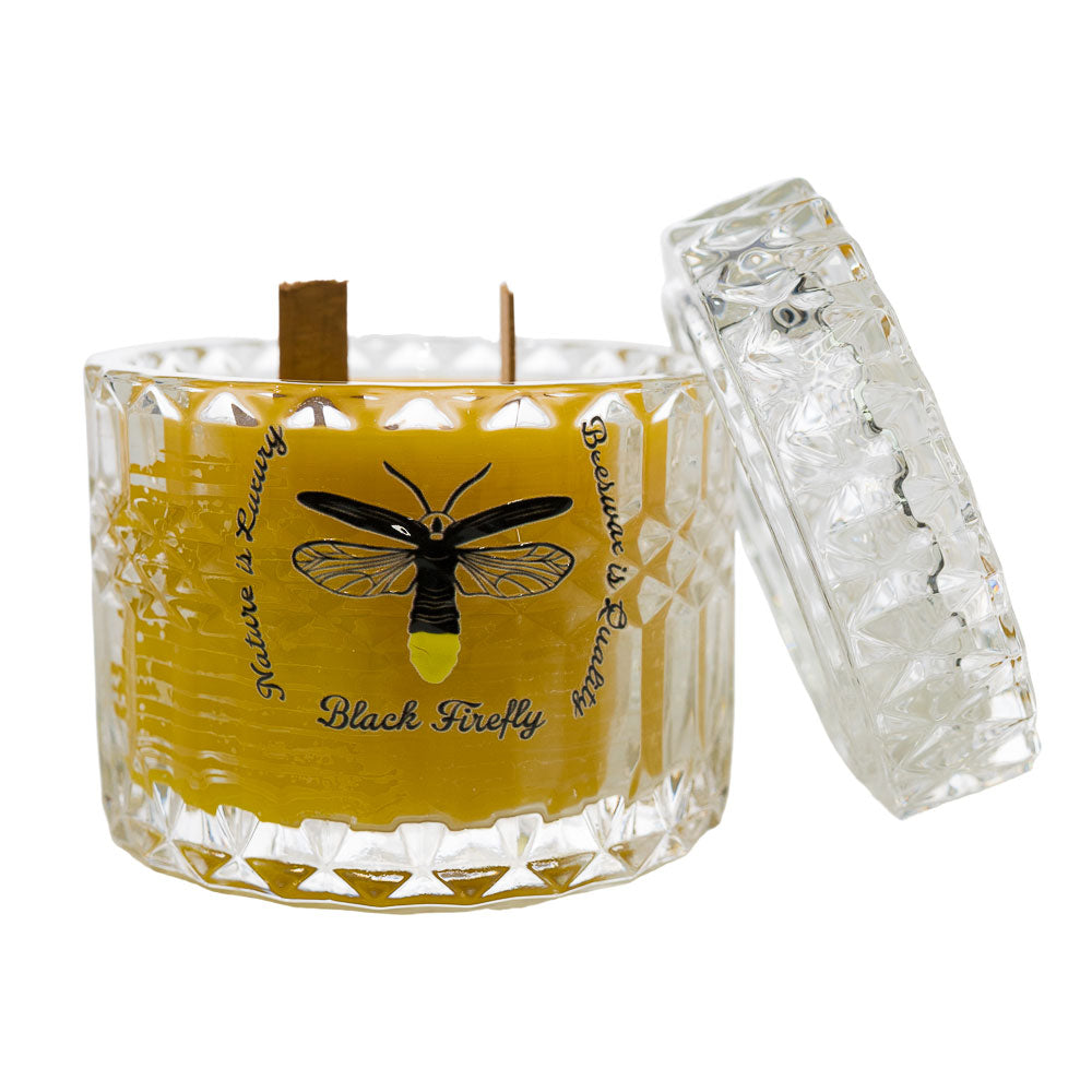 Candle with a yellow label featuring a black firefly design on a white background