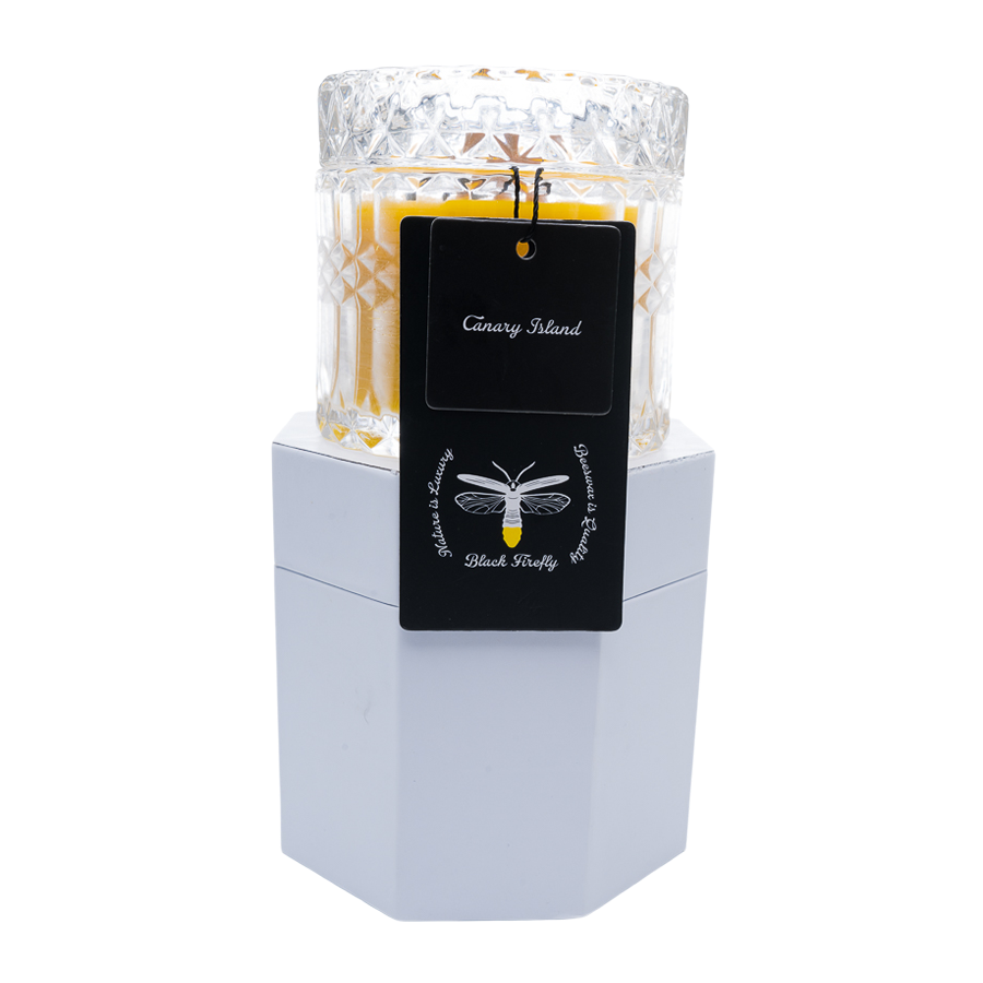 Candle in a glass holder with a black tag on a white background