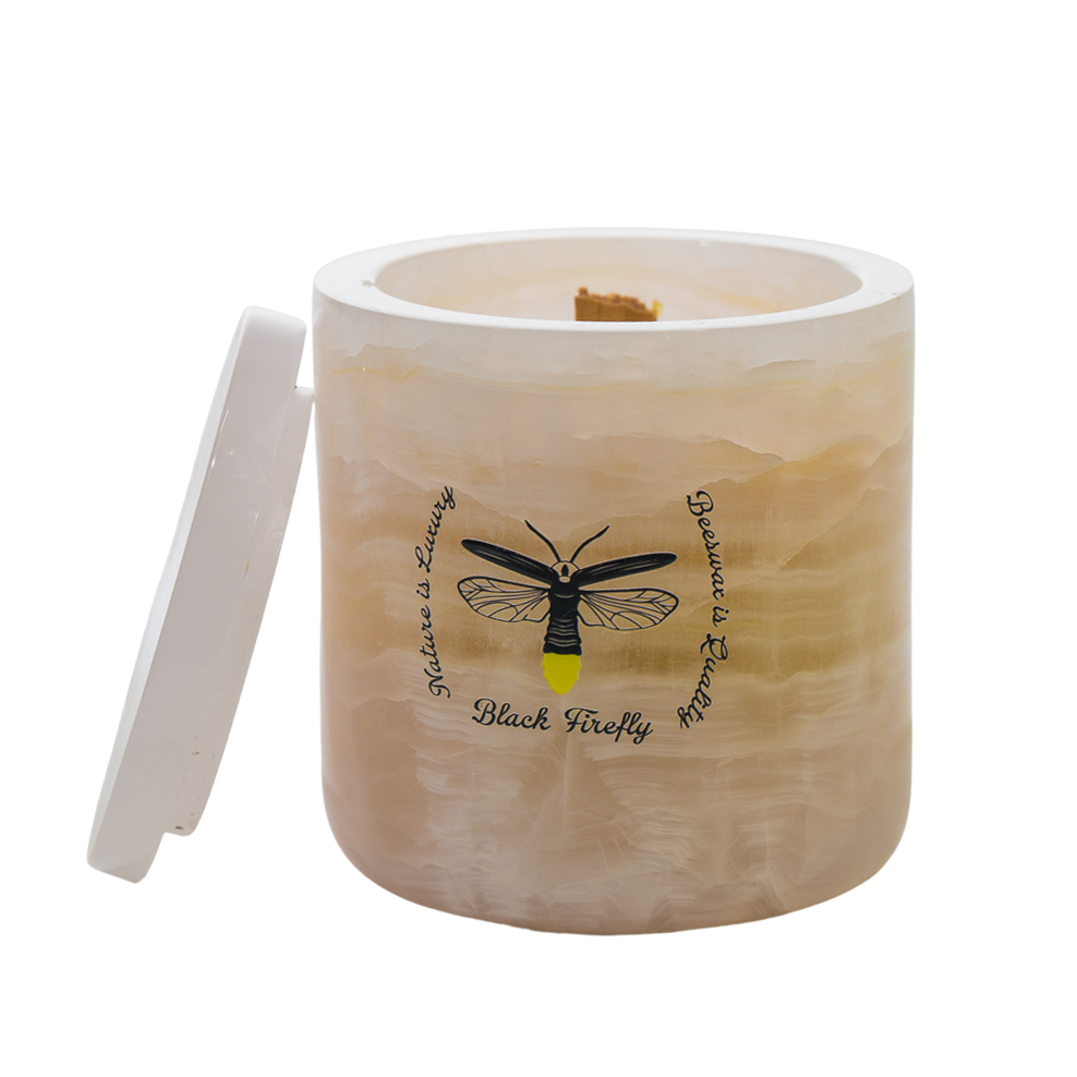 Candle in an onyx container with a lid featuring a black firefly design on a white background.